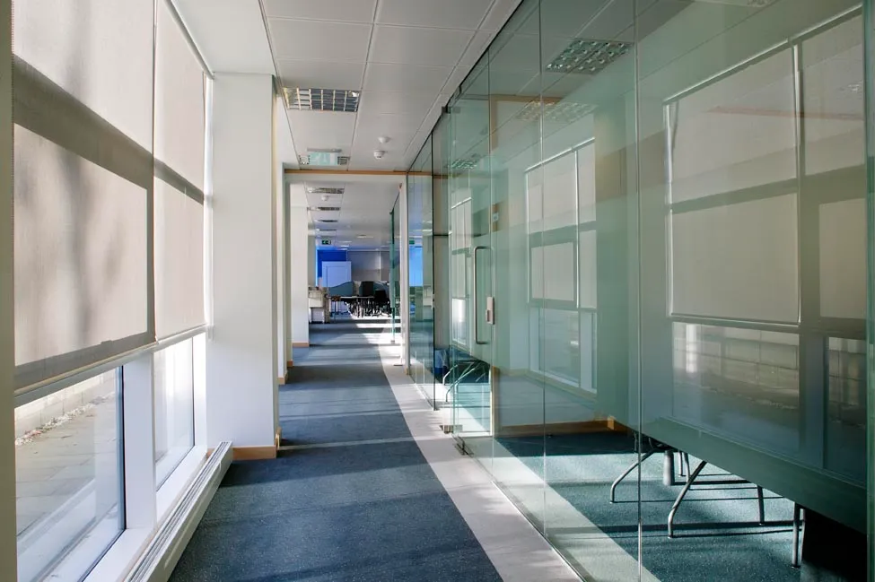 A long hallway with glass walls and a bench.