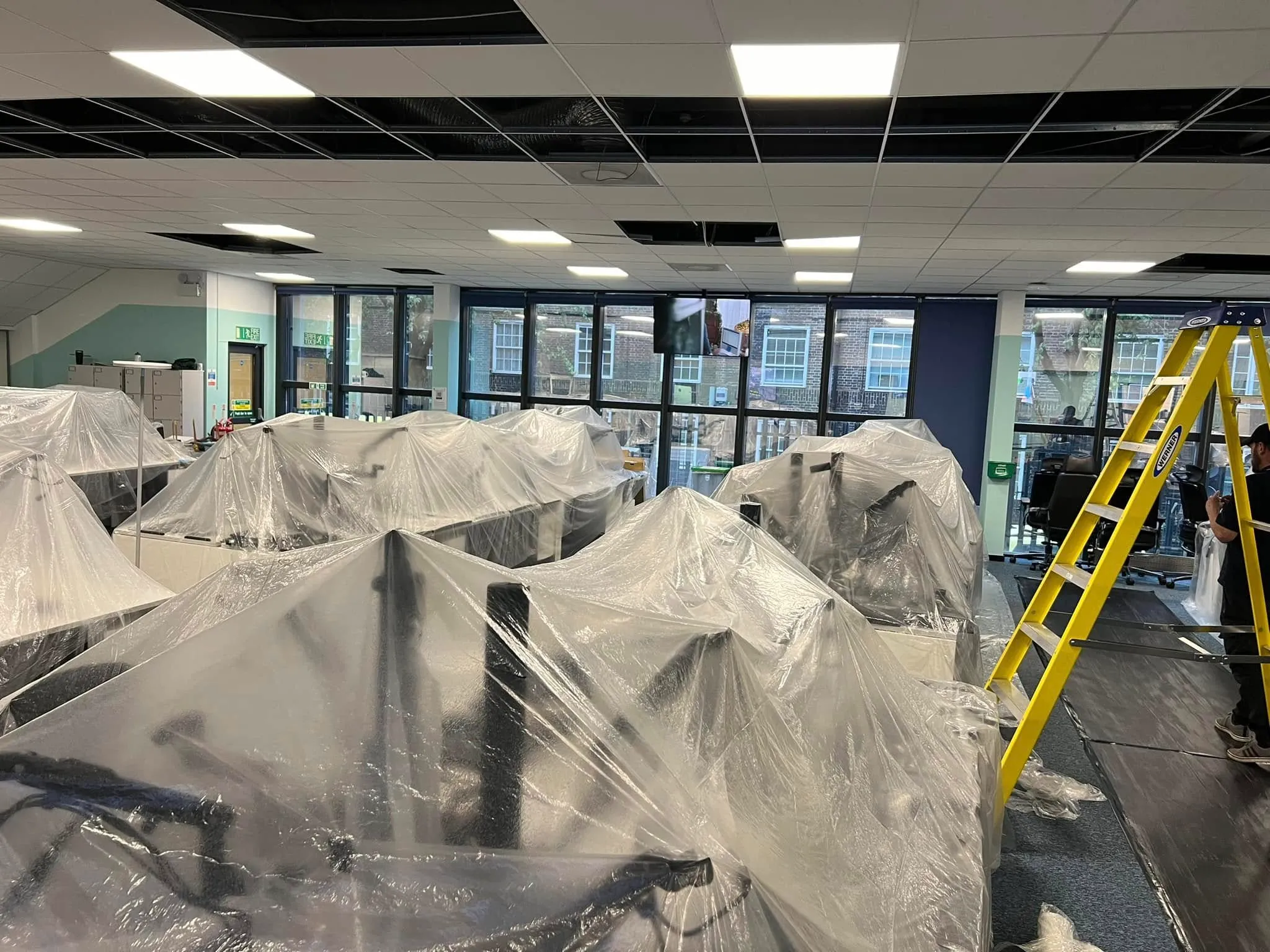 A group of people standing around a room covered in plastic.