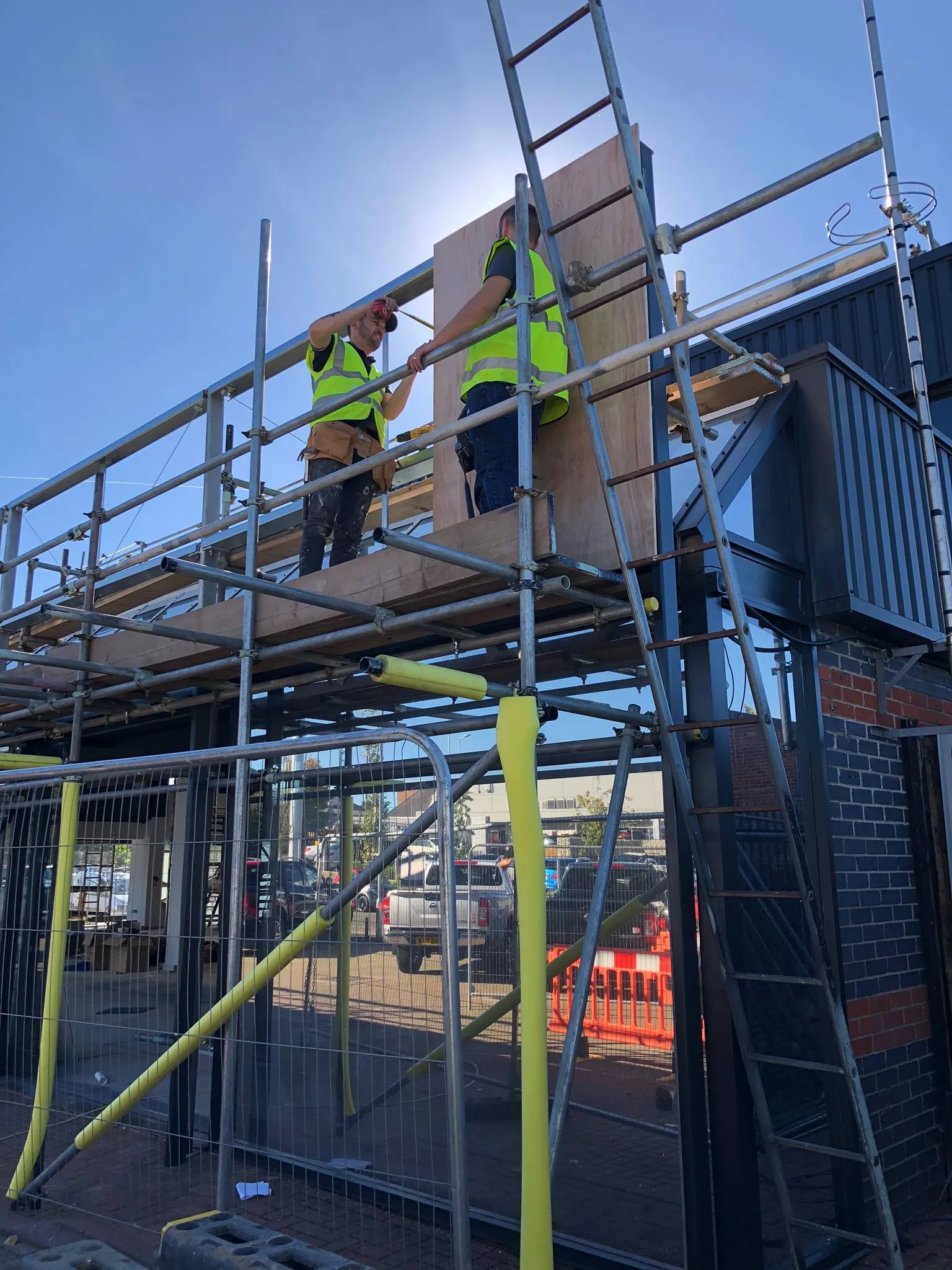 A couple of men standing on top of a metal scaffold.