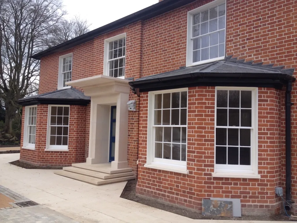A red brick house with white windows and a blue door.