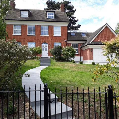 A large brick house with a black fence around it.