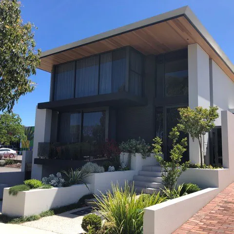 A house with a lot of plants in front of it.