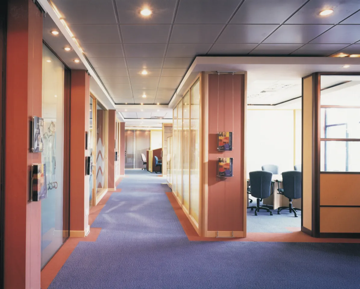 An office hallway with a blue carpet and orange walls.